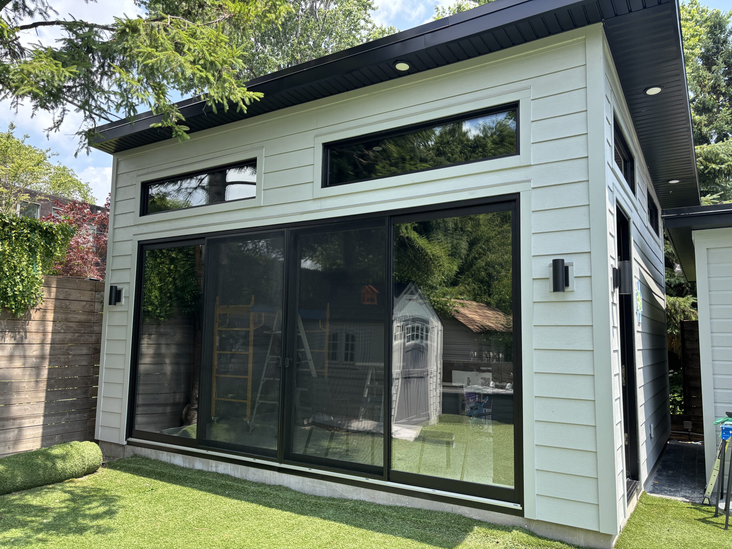 Completed modern backyard addition with fiber cement siding, black soffit and fascia installed by Kubura Siding